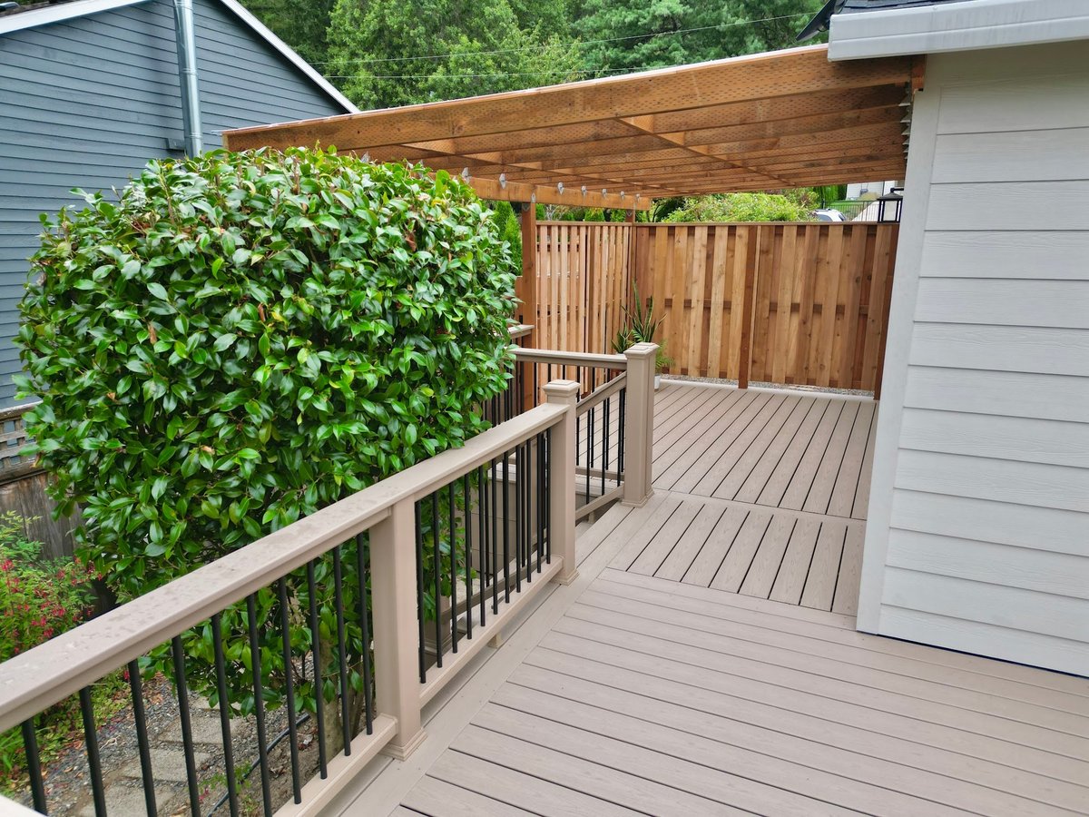 New cedar fence, painted siding and railing beside a composite walkway and pergola