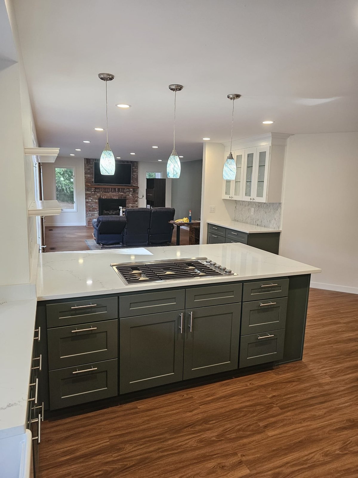 Open-concept kitchen with a quartz island and cooktop looking through to the family room