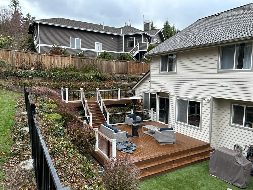 Multi-level composite deck with stairs and white railings stepping up a sloped backyard