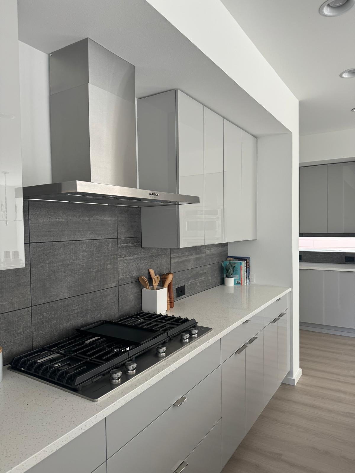 Modern kitchen with high-gloss flat-panel cabinets, a stainless chimney hood and gas cooktop