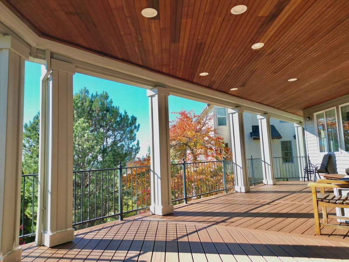 Covered composite deck with a cedar tongue-and-groove ceiling, white columns and views of the trees