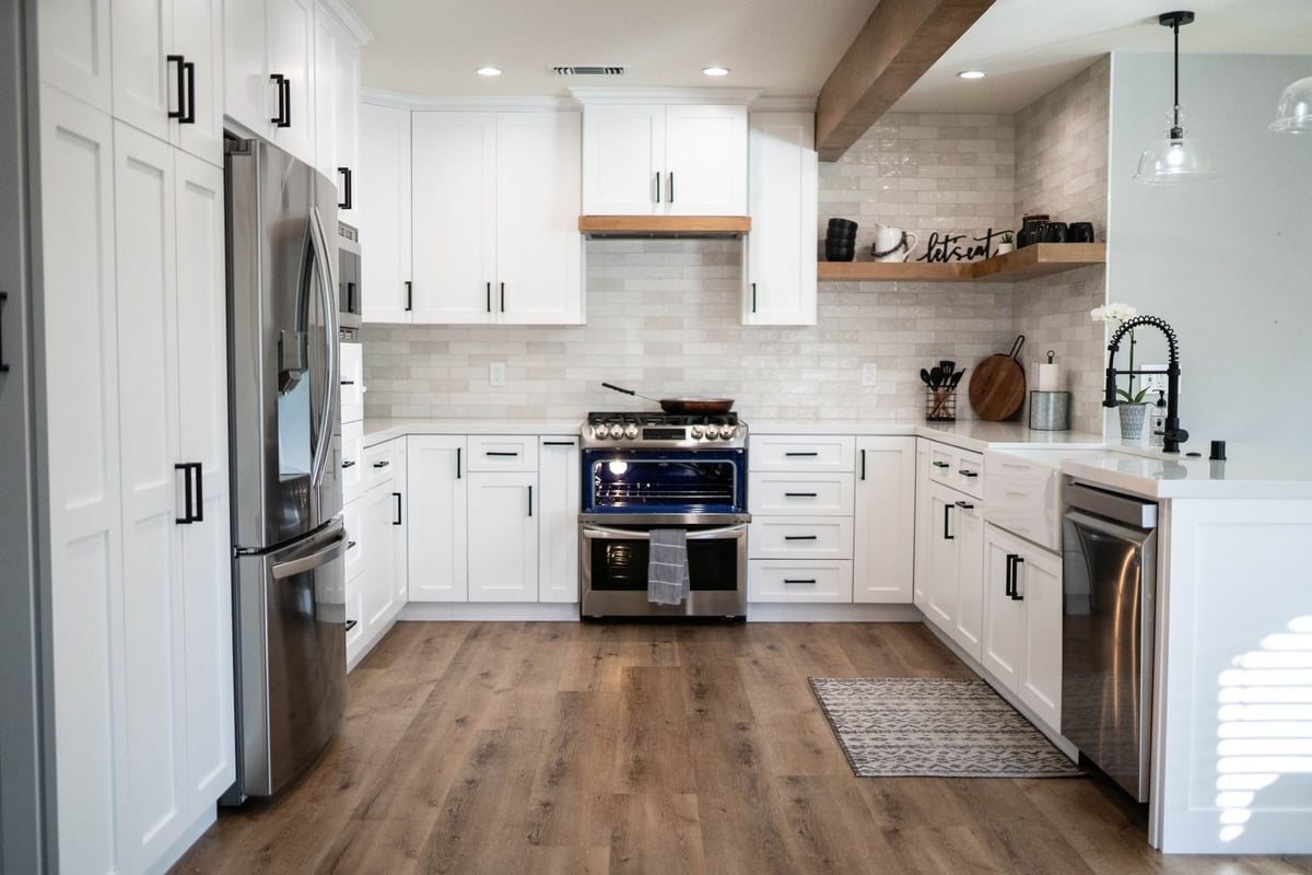 White kitchen with a stainless double-oven range, French-door refrigerator, dishwasher and recessed lighting