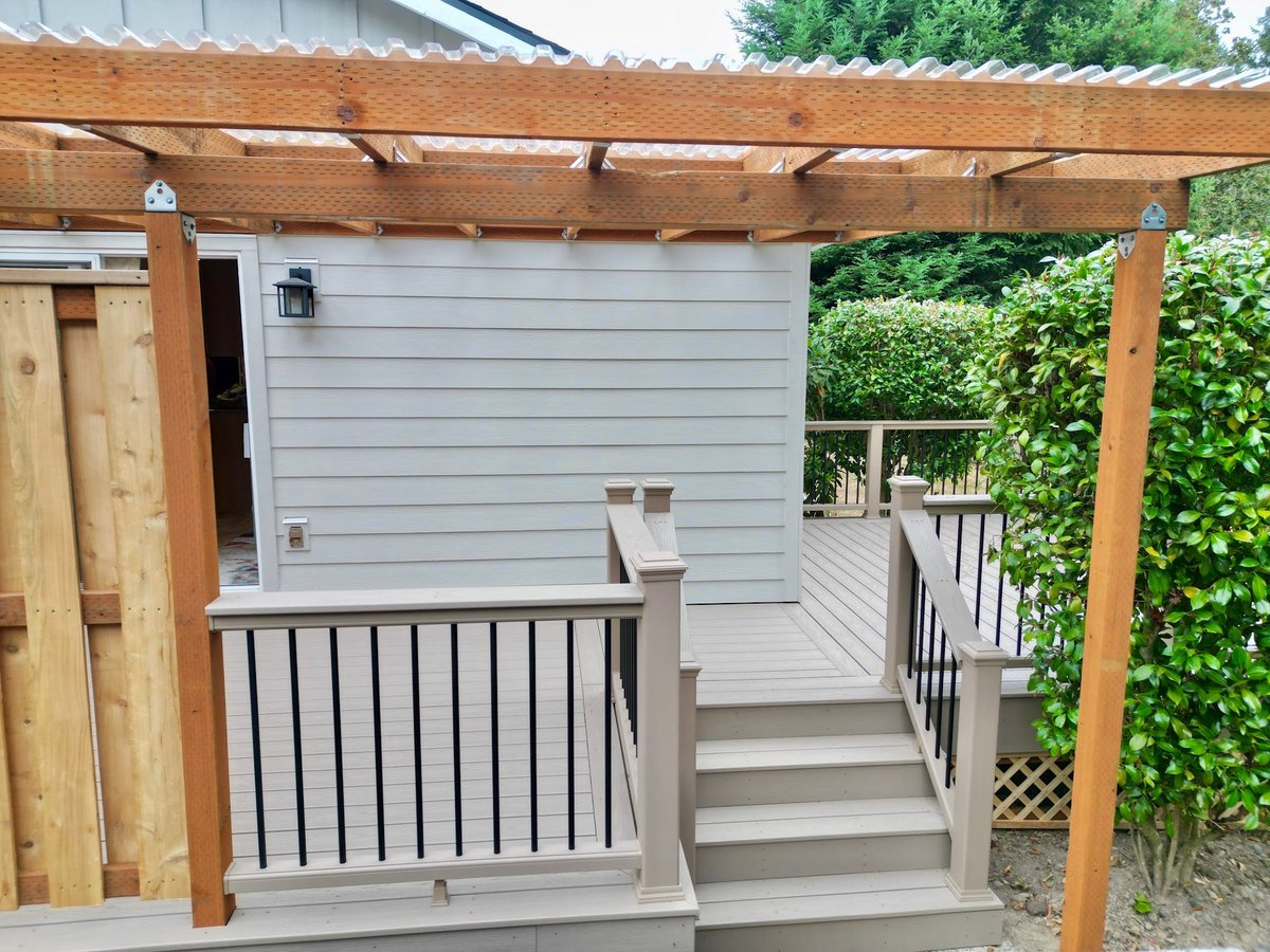 Home exterior with new siding and trim, a timber pergola and railing