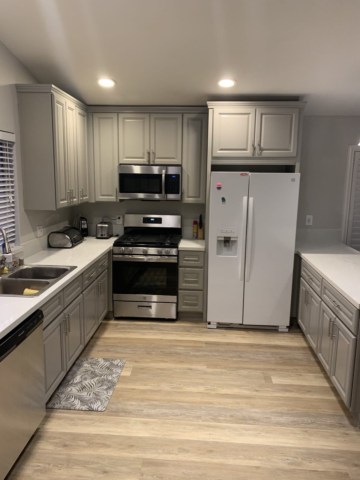 Renovated kitchen and floor area with new wood-look plank flooring, fresh paint and painted cabinets