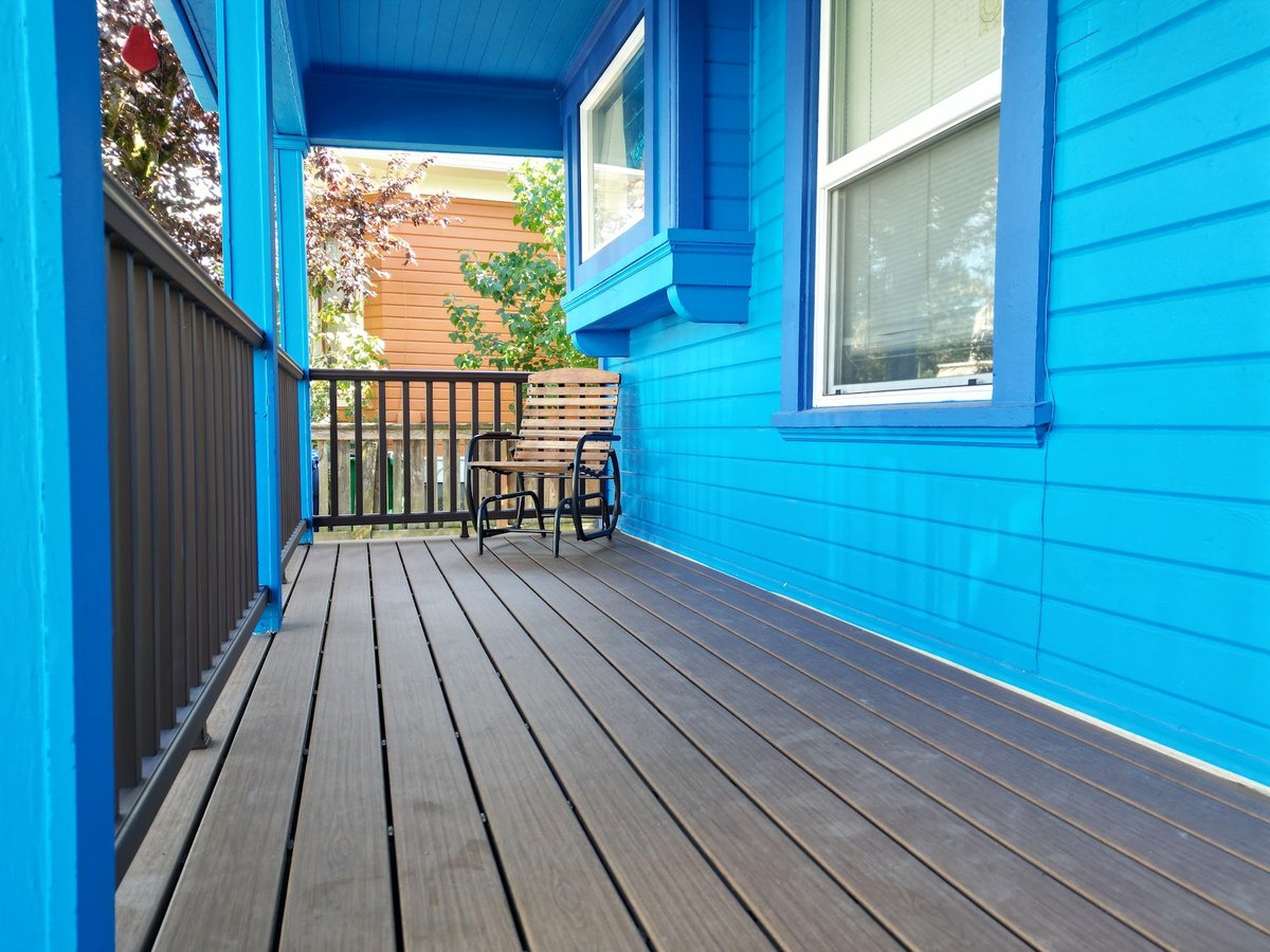 Home exterior with freshly painted blue siding, white window trim and a new dark-stained deck with railing