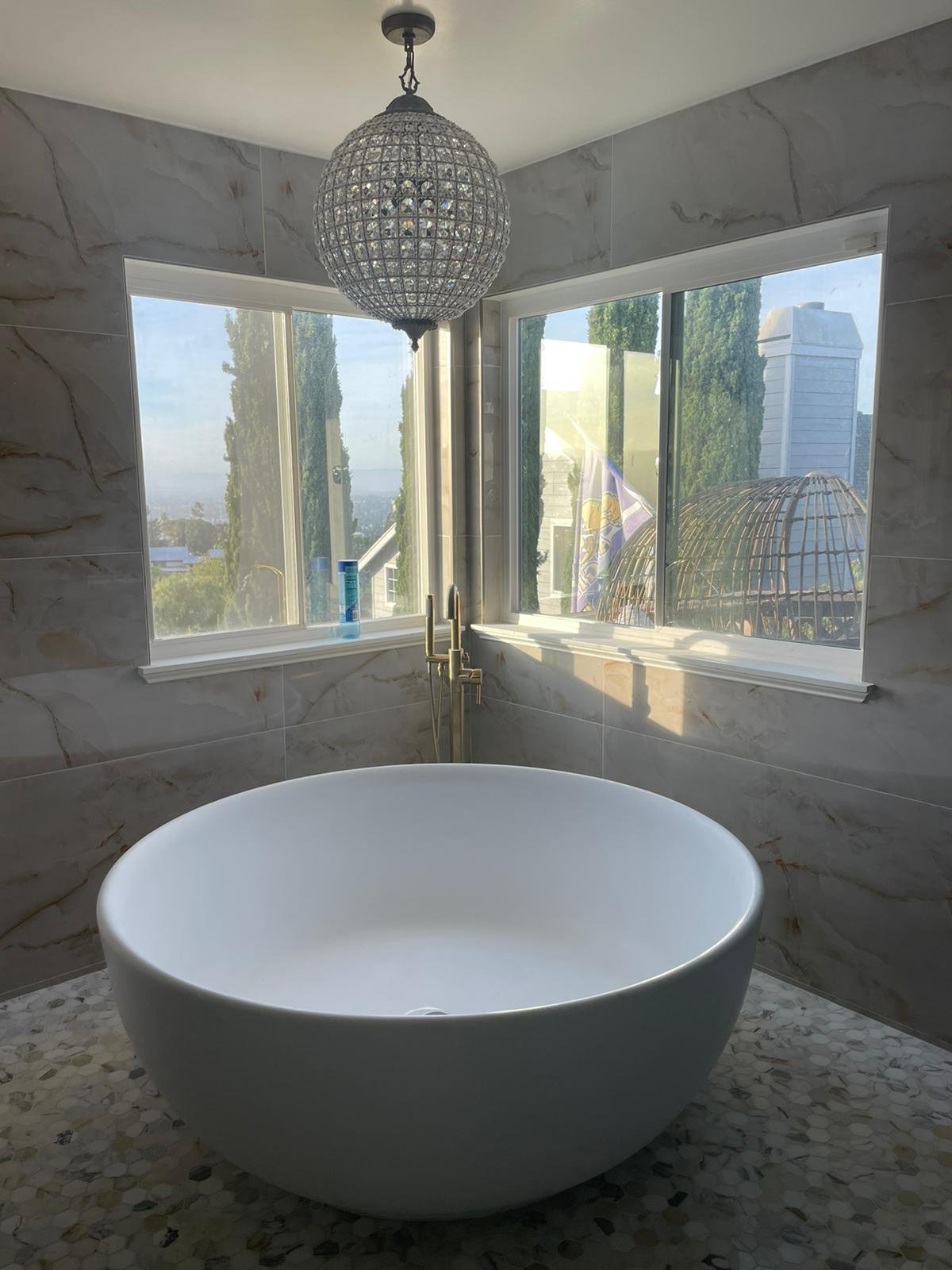 Bathroom with a round freestanding tub, two vanities with round mirrors and a large window