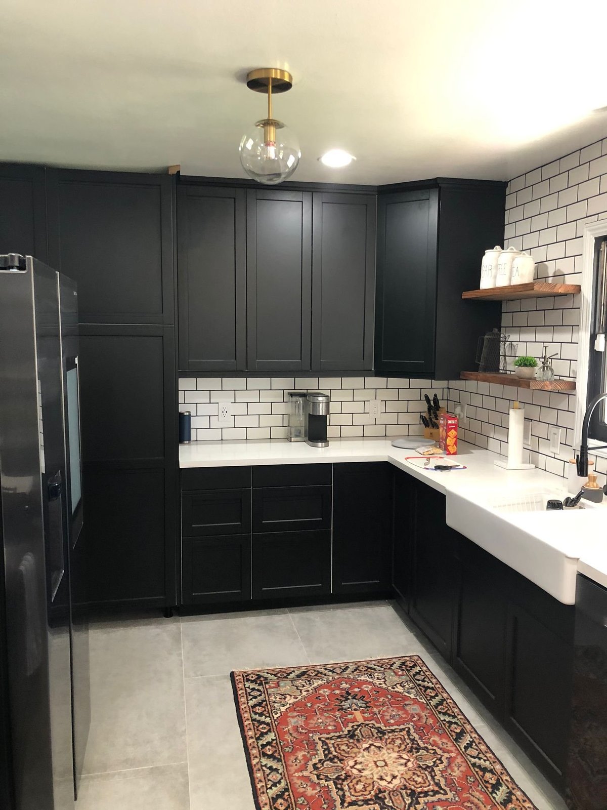 Black shaker kitchen with white subway tile, open shelving and a farmhouse sink