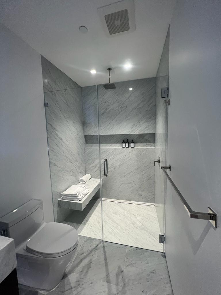 Curbless-style walk-in shower with a built-in bench, grab bar and marble-look tile