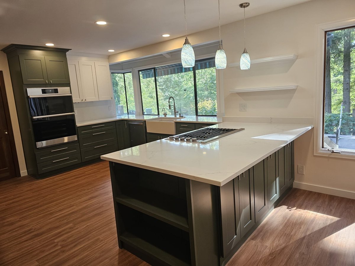 Remodeled kitchen with sage green shaker cabinets, a quartz peninsula with cooktop and a wall of windows