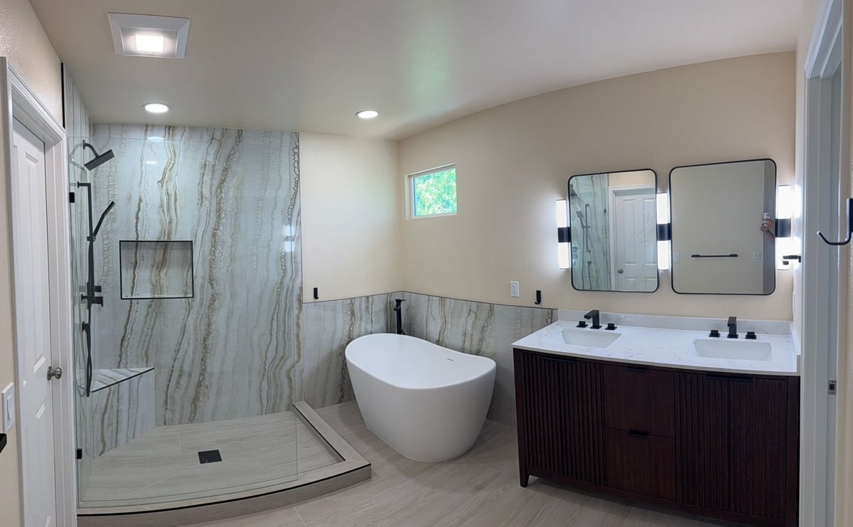 Remodeled bathroom with a slab-look shower, freestanding tub and dark double vanity