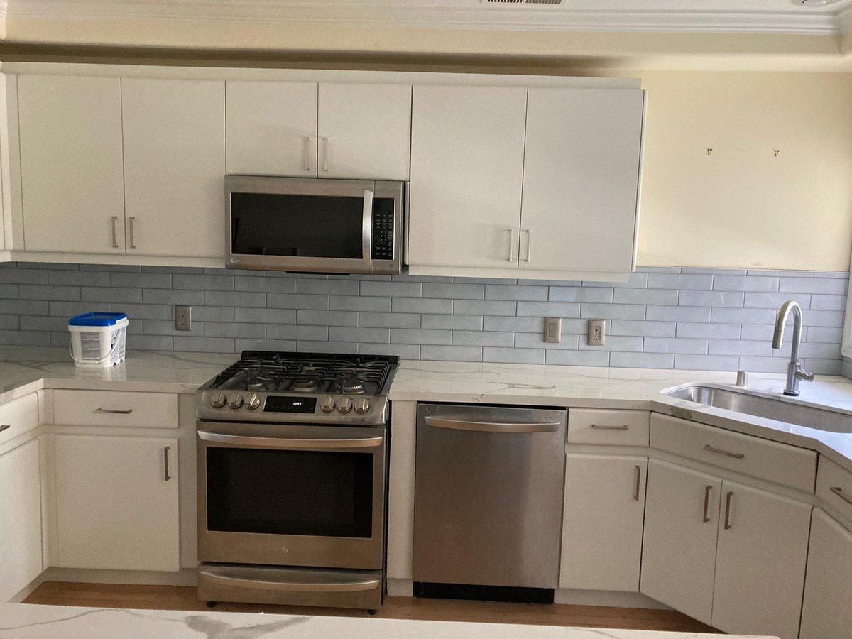 White shaker kitchen with glossy gray subway backsplash, gas range and stainless dishwasher