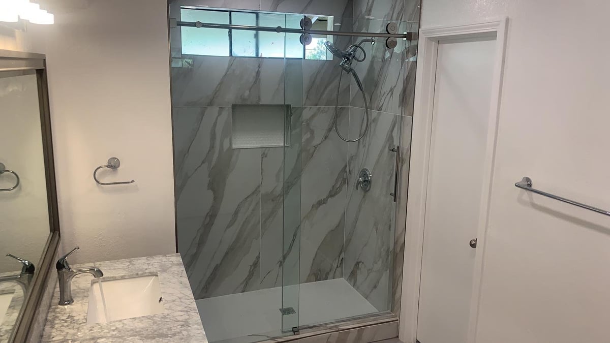 Remodeled bathroom with a marble-look walk-in shower, glass door and vanity