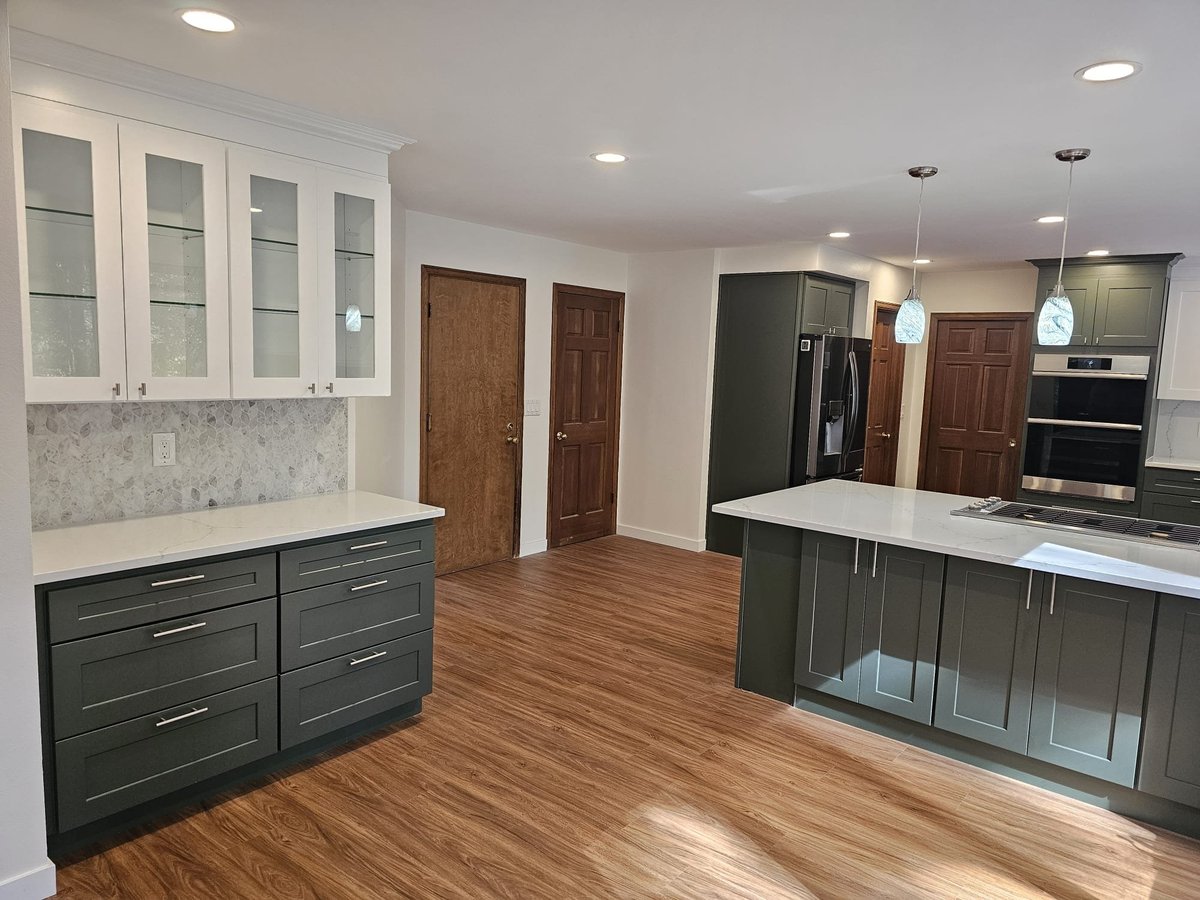Renovated room with green kitchen cabinets, glass-front uppers, new flooring and wood doors