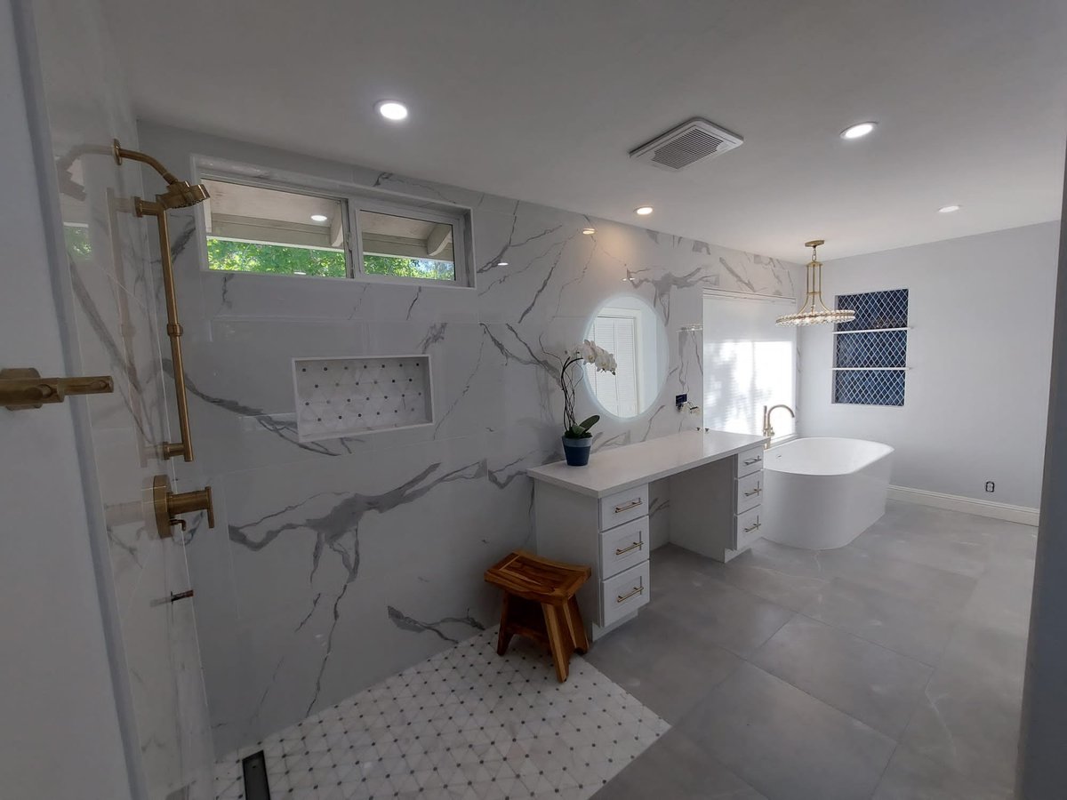 Primary bathroom with a marble-look walk-in shower, brushed brass fixtures, makeup vanity and freestanding tub